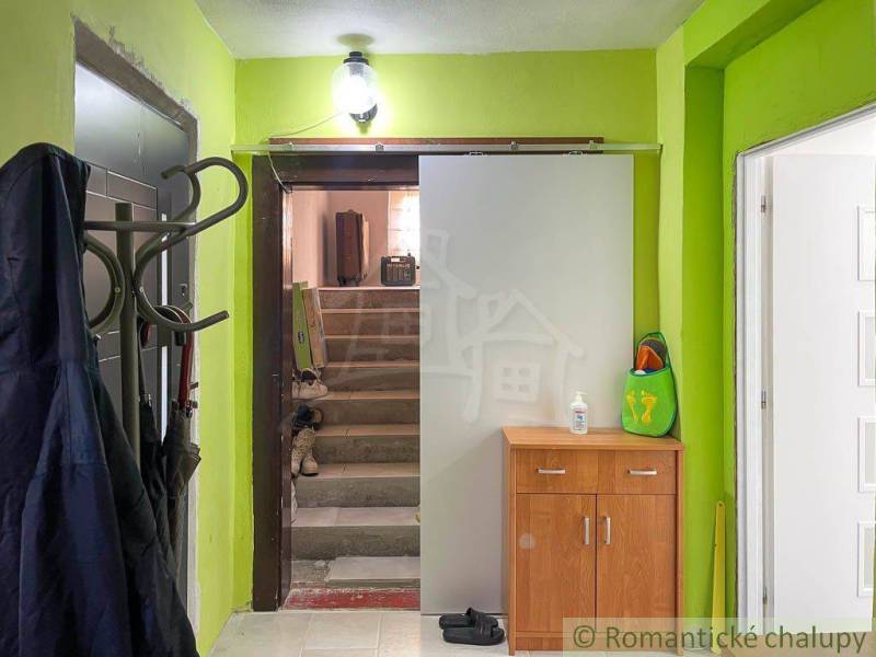 A hallway in a family house with a coat rack, a cabinet, and stairs.