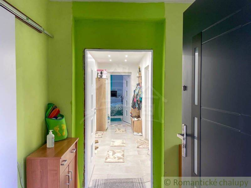 Hallway in a family house with colorful walls and a view into another room.