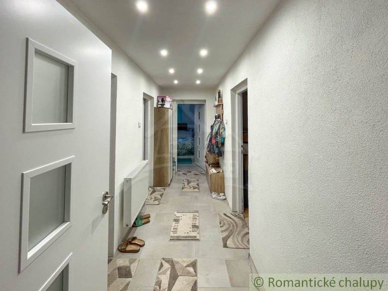 A hallway in a family house with lighting and tiled flooring.