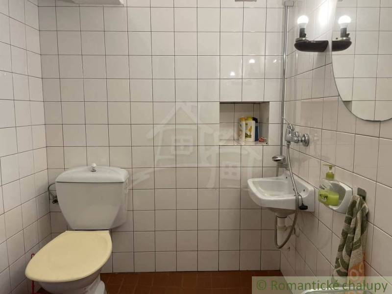 Bathroom with a toilet, sink, lights, and white tiles, peculiar property.