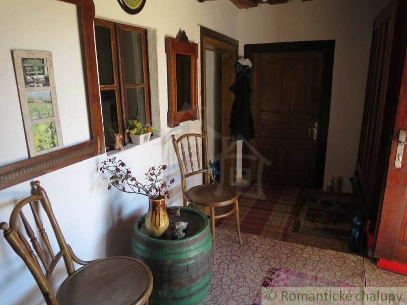 An entrance hall decorated with traditional chairs, a barrel, and floral decorations, a peculiar property.