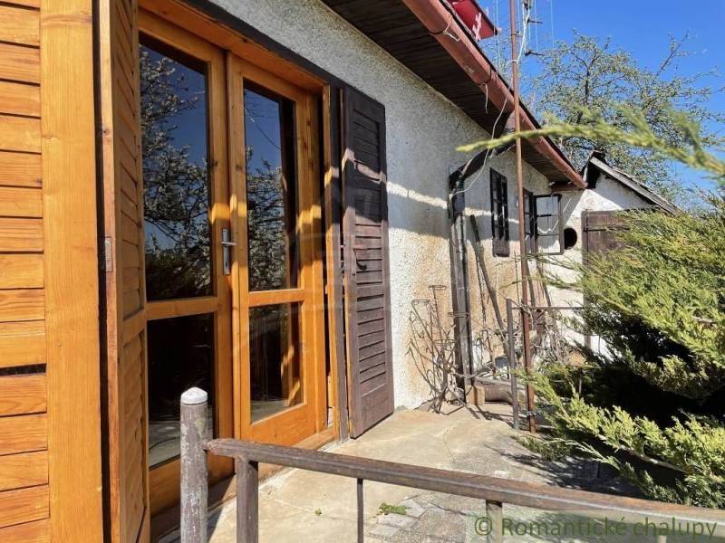The exterior of the cottage with old wooden doors and greenery, ideal for unique properties.