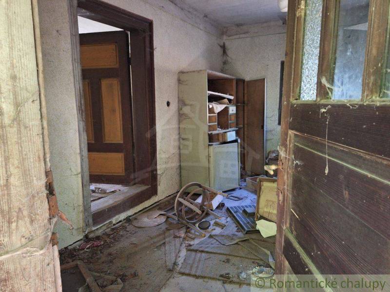 Abandoned interior of a cabin with wooden doors and old furniture.