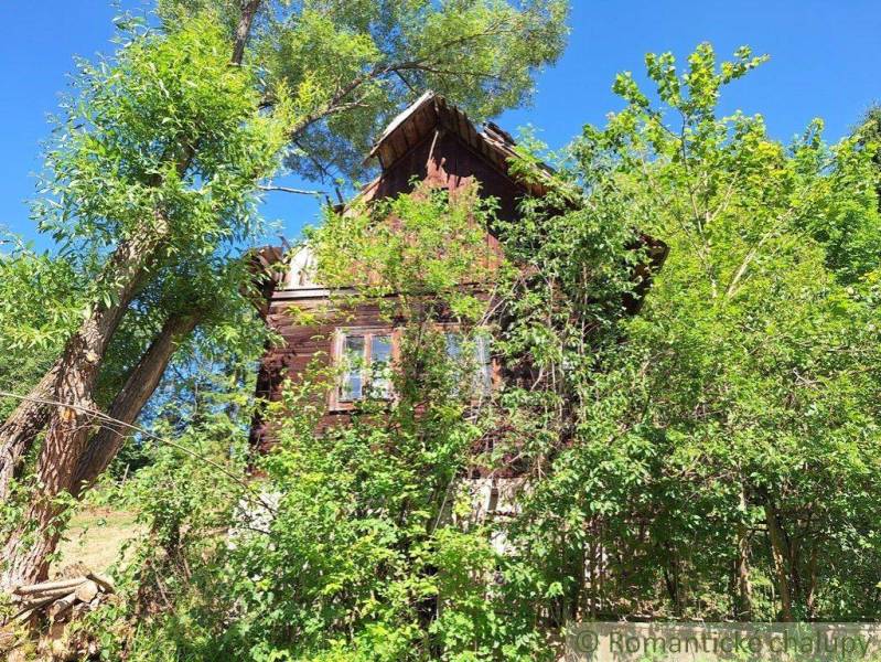 A wooden cottage in Liptovský Mikuláš surrounded by lush greenery and trees.