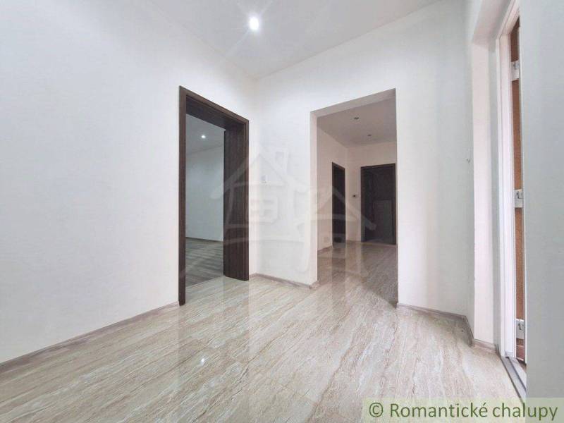 The interior of a family house with light-colored tiles and wooden doors.