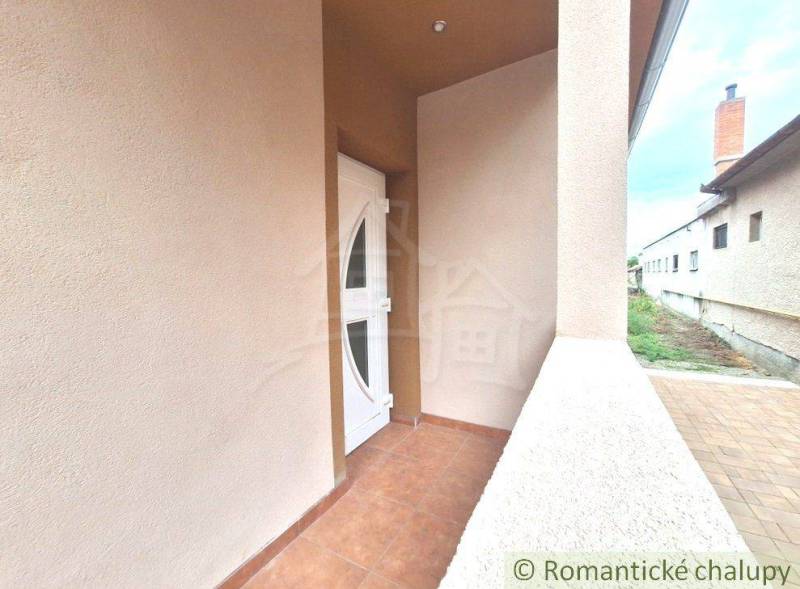 The entrance terrace of a family house in Komárno with white doors on a tiled floor.
