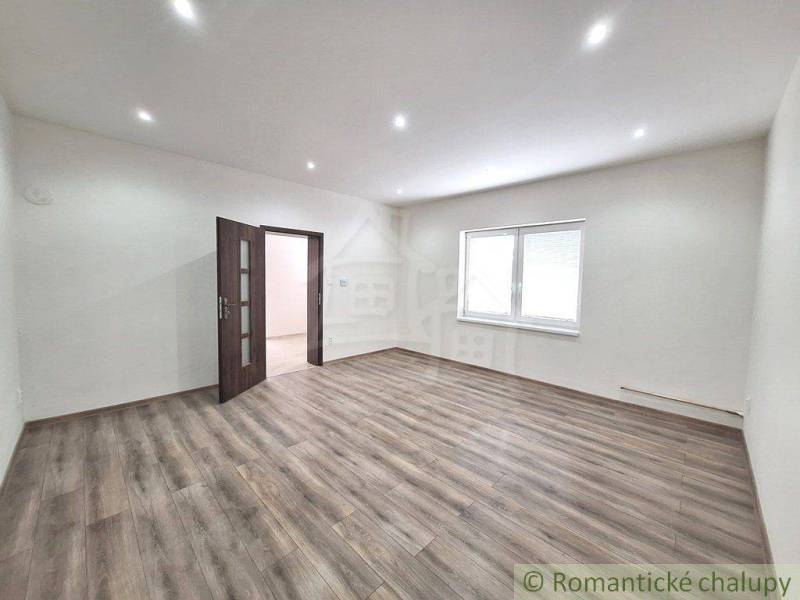 A spacious room in a family house with wooden flooring and white walls.