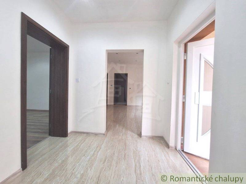 The hallway of a family house with laminate flooring and white walls.