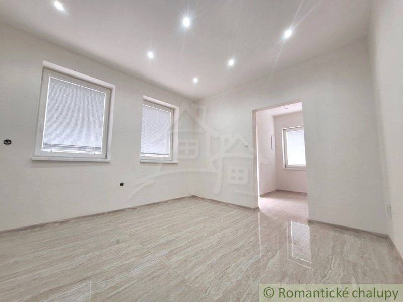 Empty room in a family house with glossy tiles and two windows.