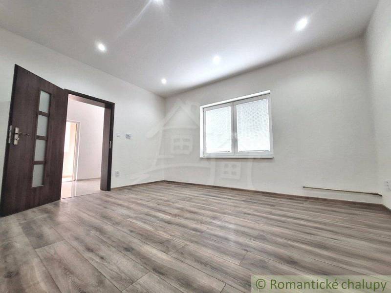 A family house with laminate flooring, white walls, and a window with internal blinds.