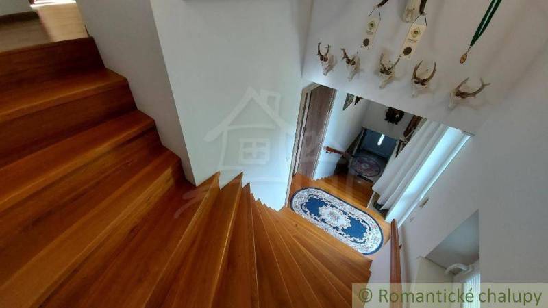 A wooden staircase in a family house with ribbons and hunting trophies on the wall.