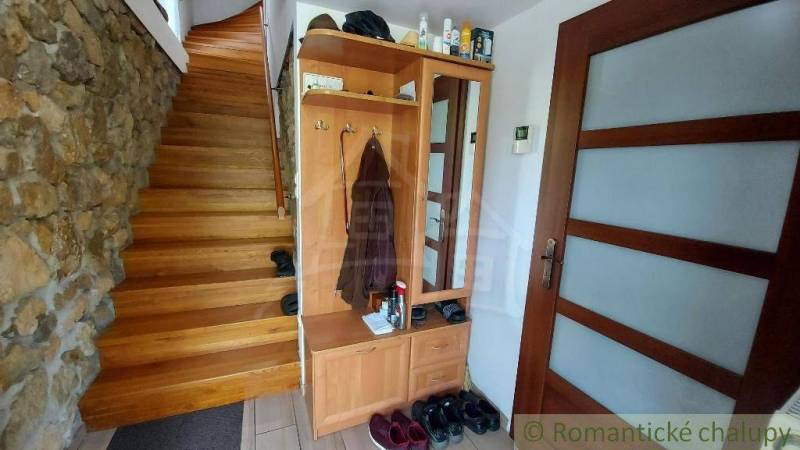 Interior of a family house with a wooden staircase, wardrobe, and stone wall.