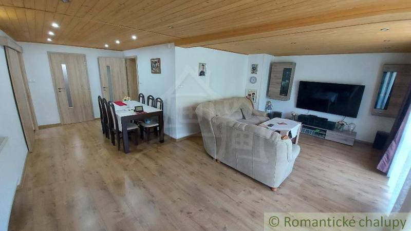 Living room and dining room in a family house with a wooden ceiling and laminate flooring.