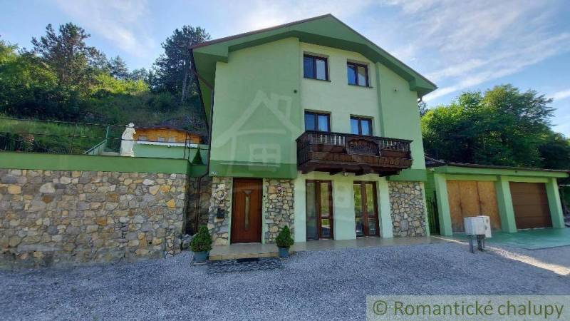 A family house in Dobrá Voda with stone details and a wooden balcony in a natural setting.