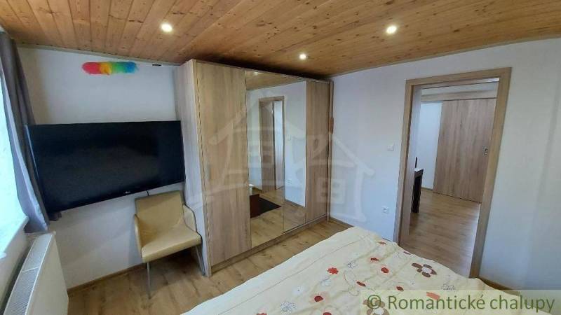 Bedroom with a wooden ceiling, bed, and cabinets in a family house.