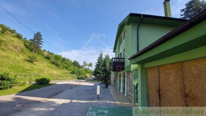 A family house in Dobrá Voda with a road, surrounding nature, and a green facade.