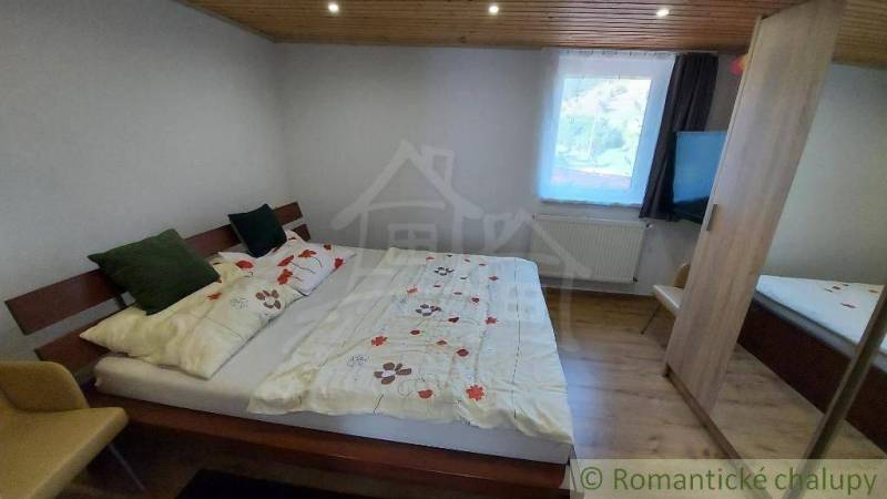 A bedroom in a family house with a cozy bed and a wooden ceiling.
