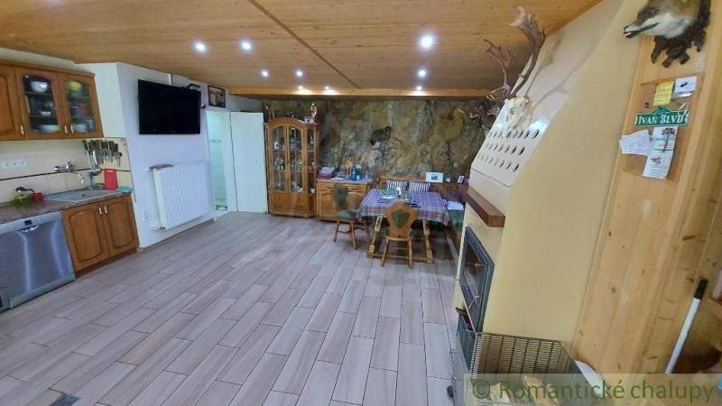Spacious kitchen with a wooden ceiling, fireplace, and dining table in a family house.