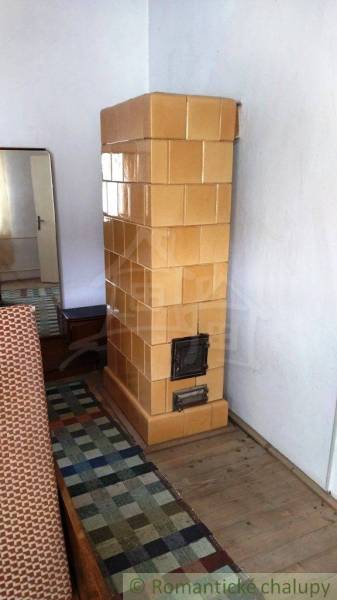 Tiled stove, wooden floor, mirror, carpet in a family house.