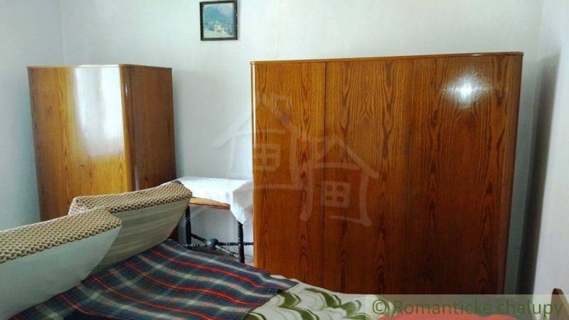 A room in a family house with antique wardrobes and a bed with a colorful blanket.