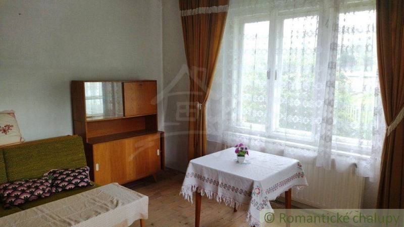 A room in a family house with a wooden dresser, a sofa, and a table by the window.