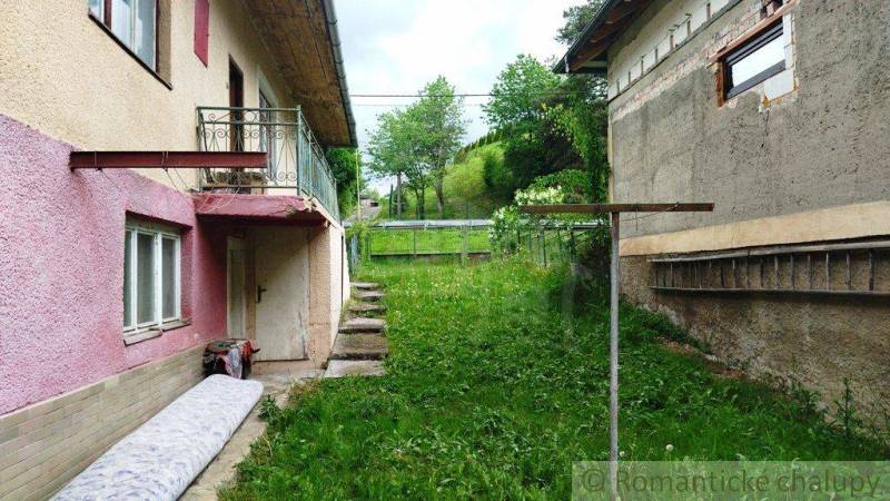 A family house in Fričovce with an unkempt garden, next to neglected facades and a staircase.