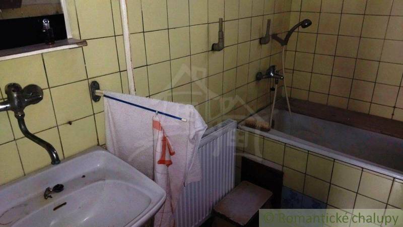 A bathroom in a family house with a sink, a bathtub, and yellow tiles.