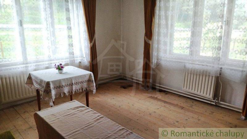 Interior of a family house with wooden flooring, a table, and long curtains.