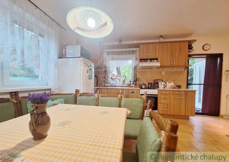 A kitchen in a family house with wooden furniture and floral decoration on the table.