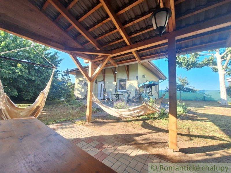 A covered terrace with swings at a family house in Komárno, surrounded by greenery.