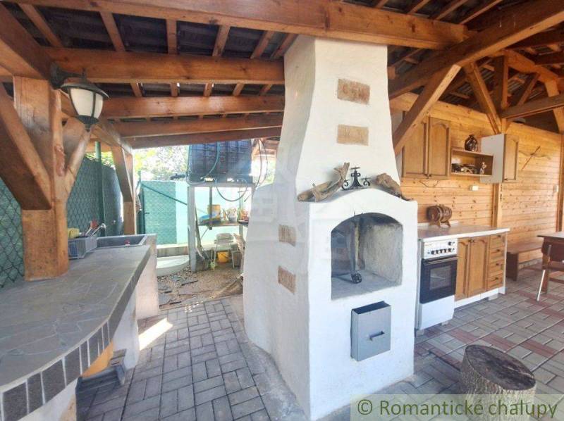 In the family house, there is an outdoor kitchen with an oven, wooden elements, and a stove.
