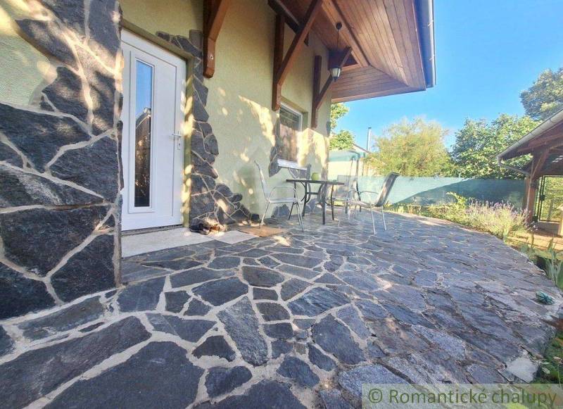 A family house in Komárno with a stone terrace, table, and chairs in the garden.