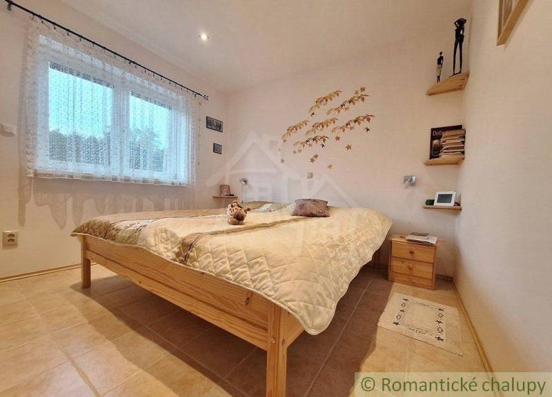 Bedroom in a family house with simple wooden furniture and decorative wall decoration.