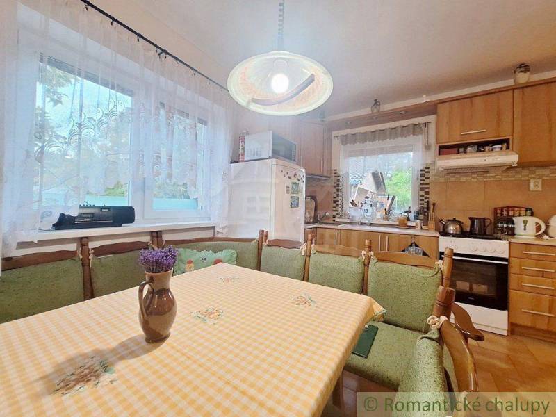 A kitchen in a family house with wooden furniture, a dining table, and an equipped kitchen unit.