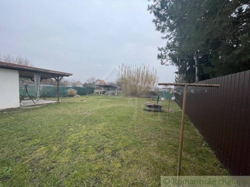 A garden with a lawn by the family house, a gazebo, and a clothesline, wooden fence.