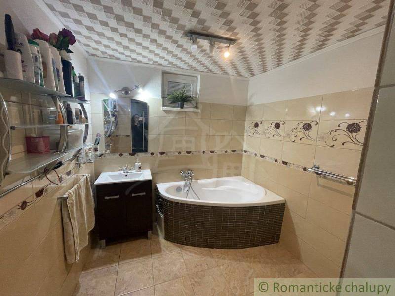 A bathroom in a family house with a bathtub, sink, tiles, and decorative details.