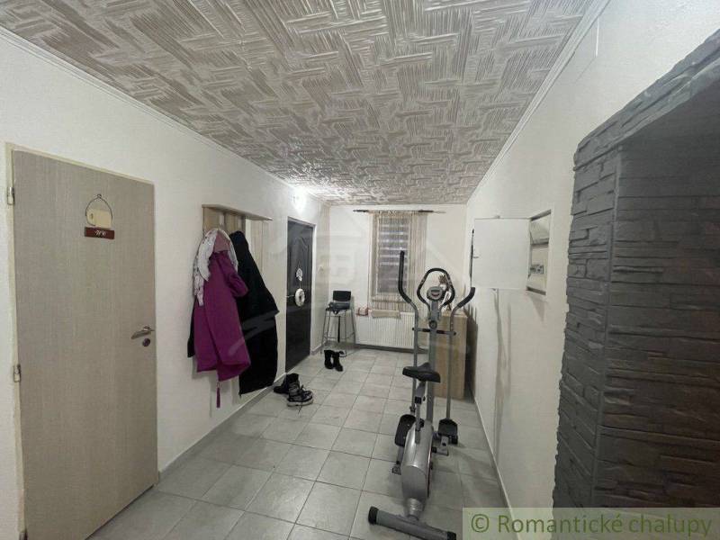 A corridor with tiles, an exercise machine, and a coat rack in a family house.