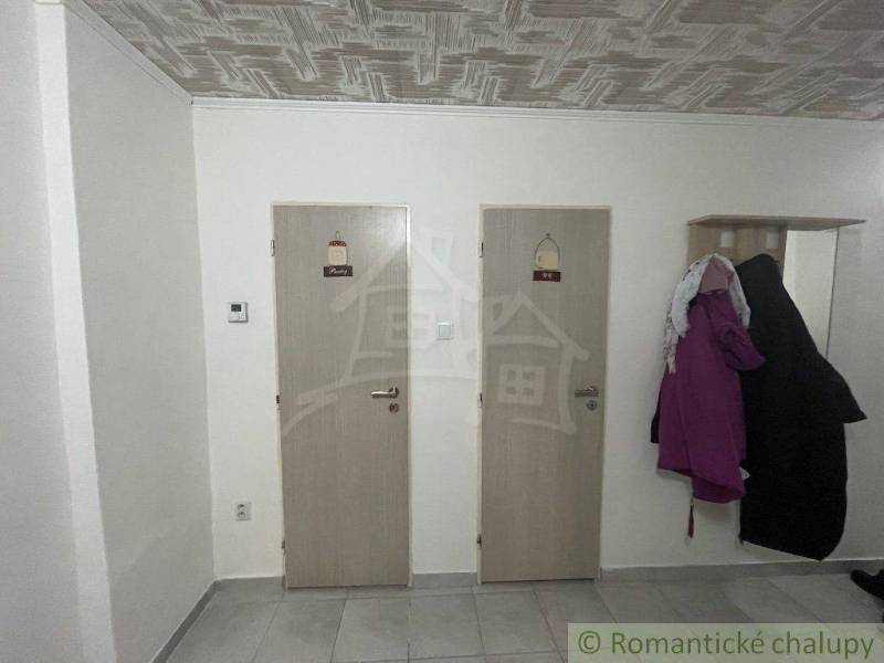 Two wooden interior doors next to a coat rack, tiles, in a family house.