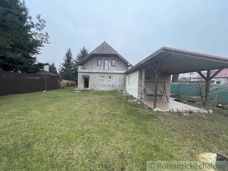 A family house with a gazebo and lawn, surrounded by trees, is located in a quiet area.