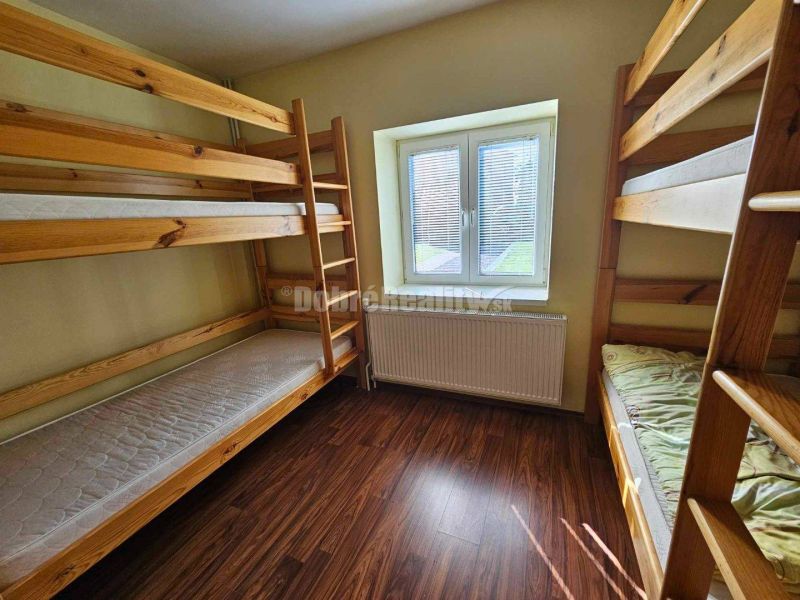 A room with bunk beds, a wooden decor floor, and soft lighting in a family house.