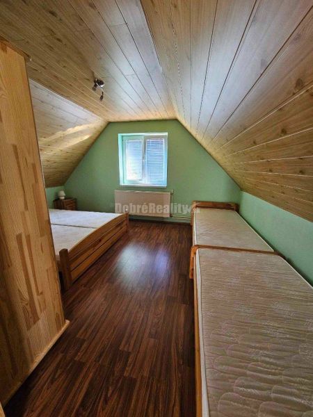 Attic room in a family house with beds and a wooden decor floor.