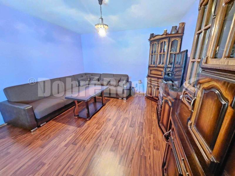 Living room in a family house, wooden furniture, corner sofa, light blue walls.
