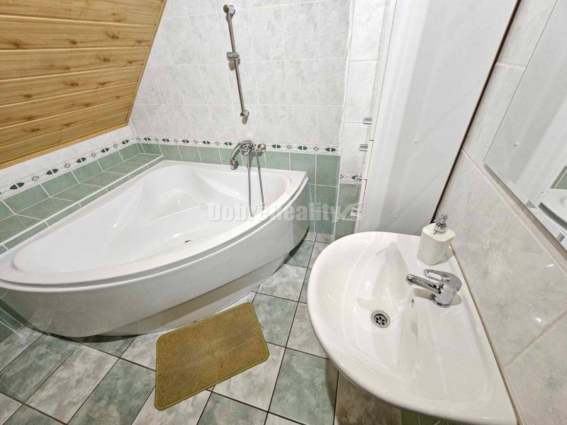 A bathroom with a corner bathtub and a sink in a family house.