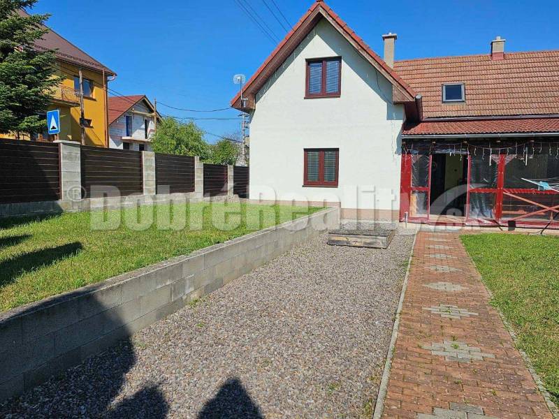 A family house in Malá Lehota with a landscaped garden, walkway, and fencing.