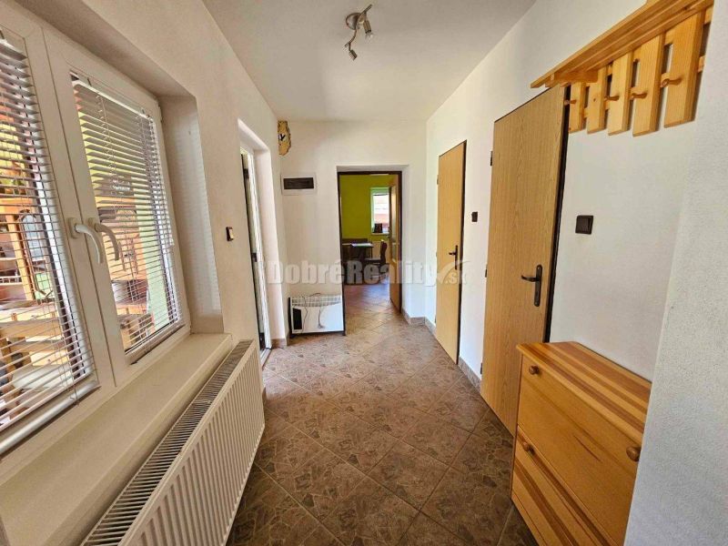 A hallway in a family house with tiles, wooden furniture, windows with blinds.