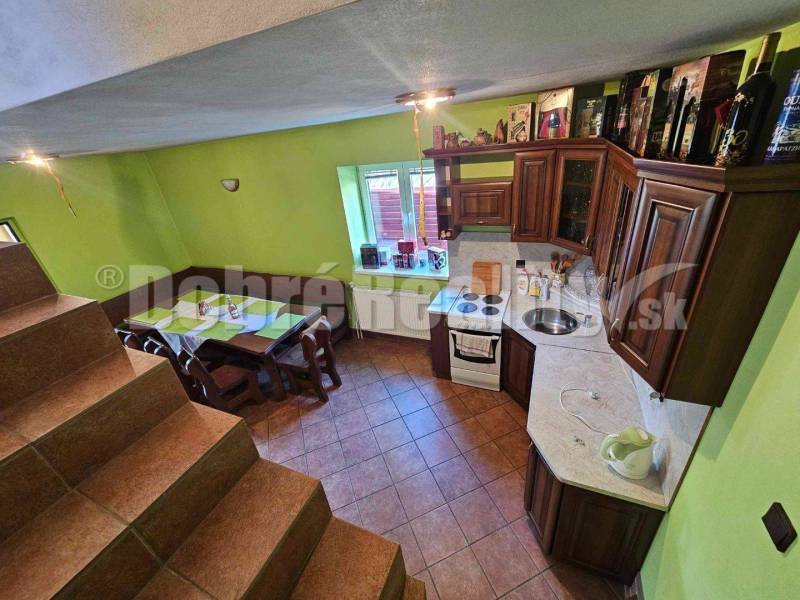 A kitchen with a wooden cabinet and a dining area, stairs in a family house.