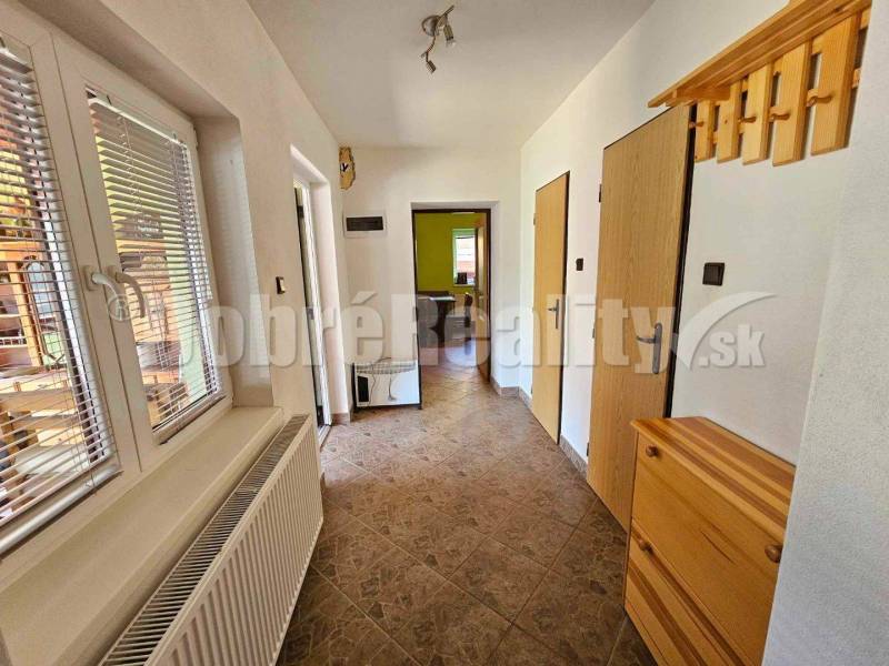Hallway in a family house with tiles, a coat rack, and a window with blinds.