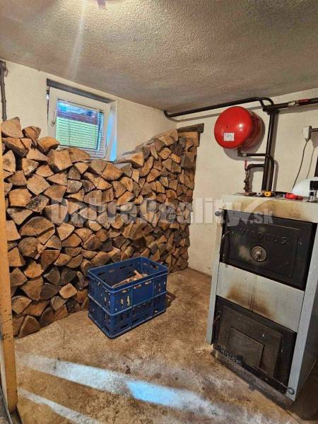 Boiler room of a family house with wood, a boiler, and a blue crate on the floor.