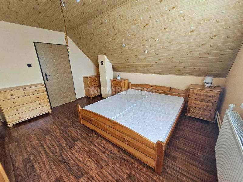 A bedroom in a family house with a wood-patterned floor and wooden furniture.