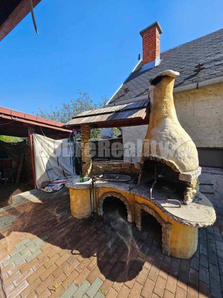 The exterior of a family house in Malá Lehota with a brick chimney and a masonry fireplace on the terrace.